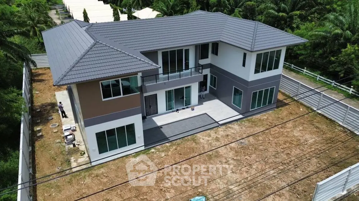 Modern two-story house with spacious yard and lush greenery, perfect for family living.