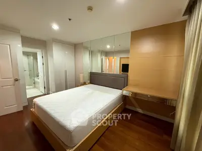 Modern bedroom with wooden flooring and ensuite bathroom in a stylish apartment.