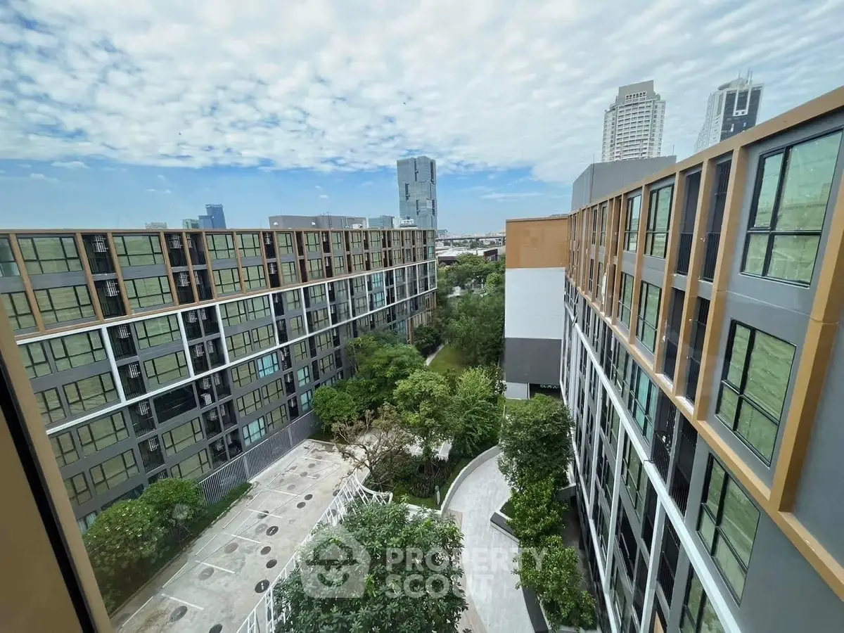 Modern urban apartment complex with lush greenery and city skyline view.