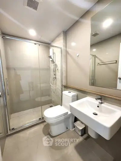Modern bathroom with glass shower and sleek fixtures in contemporary apartment.