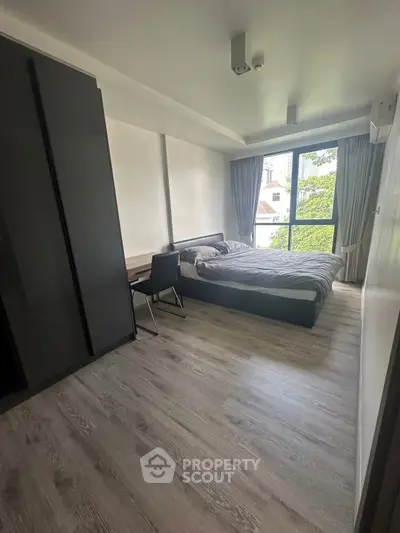 Modern bedroom with large window and stylish furnishings in a contemporary apartment.
