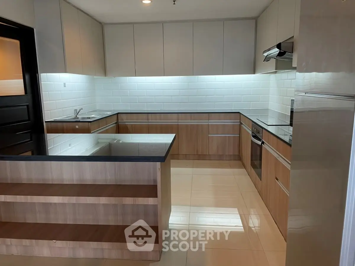 Modern kitchen with sleek cabinetry and built-in appliances, featuring a spacious countertop and elegant tile backsplash.