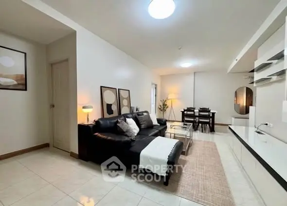 Spacious modern living room with sleek black sofa and elegant dining area