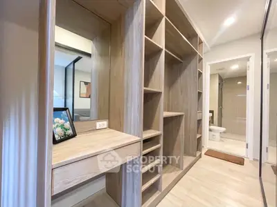 Spacious walk-in closet with elegant wooden shelving and a vanity area, adjacent to a modern bathroom.