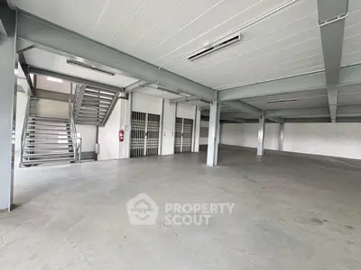 Spacious industrial warehouse with metal beams and concrete flooring, ideal for storage or manufacturing.
