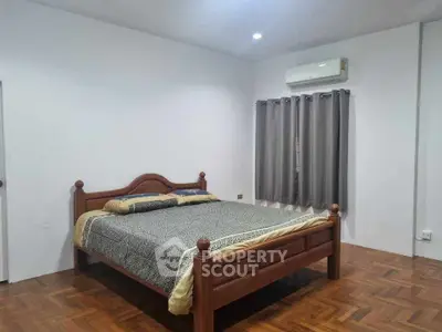 Spacious bedroom with wooden bed and parquet flooring, featuring modern air conditioning.