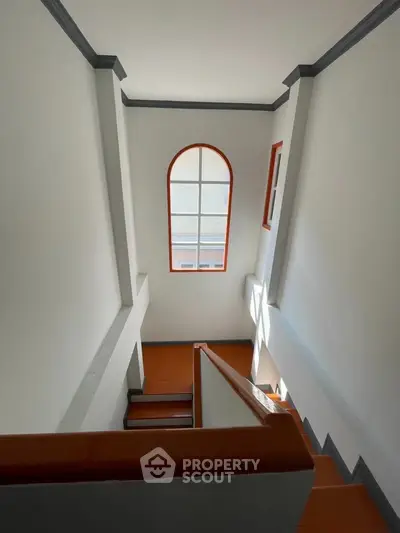 Elegant staircase with arched window and natural light in modern home