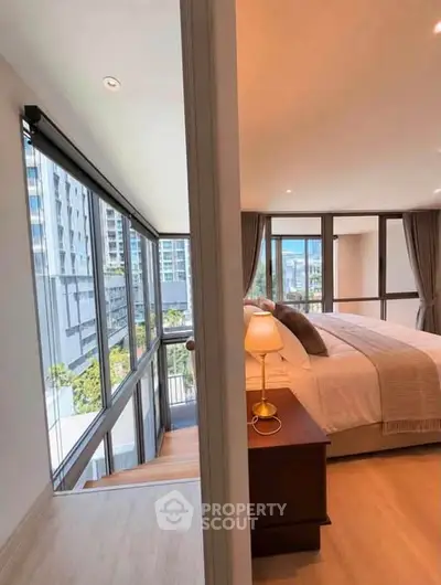 Luxurious bedroom with floor-to-ceiling windows offering stunning city views in a modern apartment.