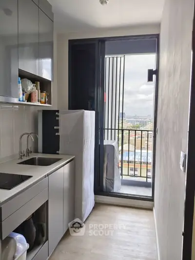 Modern kitchen with sleek cabinets and balcony view in urban apartment