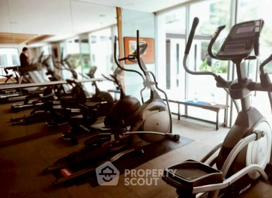 Modern gym with exercise equipment and mirrored walls in a luxury residential building.