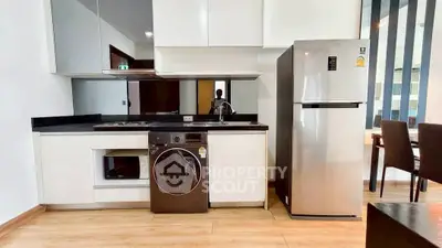 Modern kitchen with sleek appliances and wooden flooring in a stylish apartment.