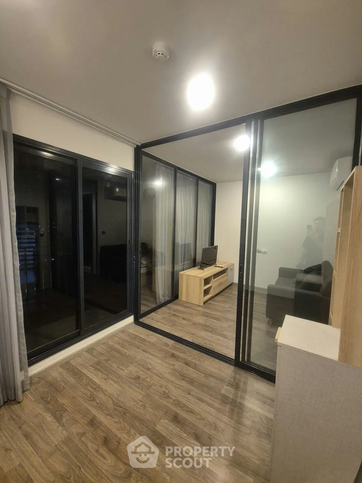 Modern living room with glass partition and wooden flooring in a stylish apartment.