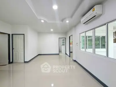 Spacious modern living room with air conditioning and large windows for natural light.