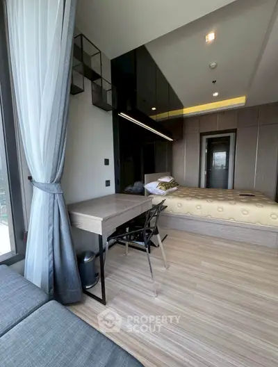 Modern bedroom with stylish decor and natural light, featuring a cozy bed and sleek workspace.