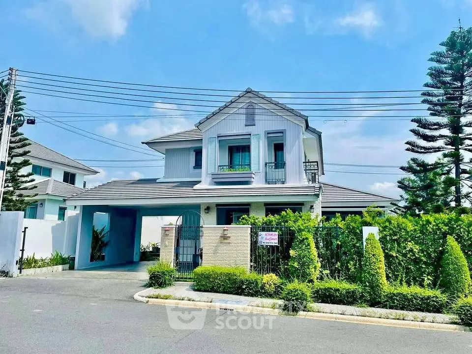 Charming two-story house with lush garden and gated entrance in serene neighborhood.