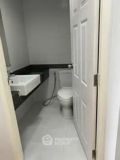 Compact bathroom with modern fixtures and white tiles, featuring a sleek sink and toilet.