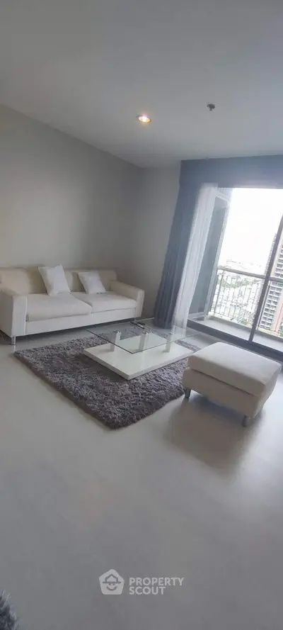 Spacious modern living room with elegant sofa and city view balcony.