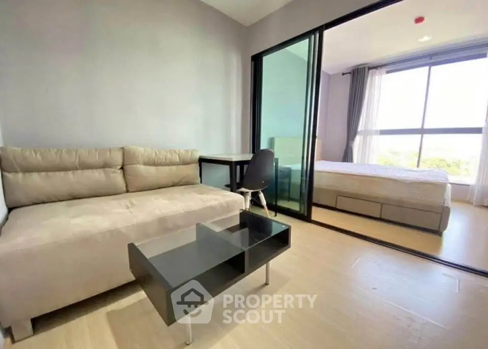 Modern studio apartment with cozy living area and bedroom separated by glass doors.