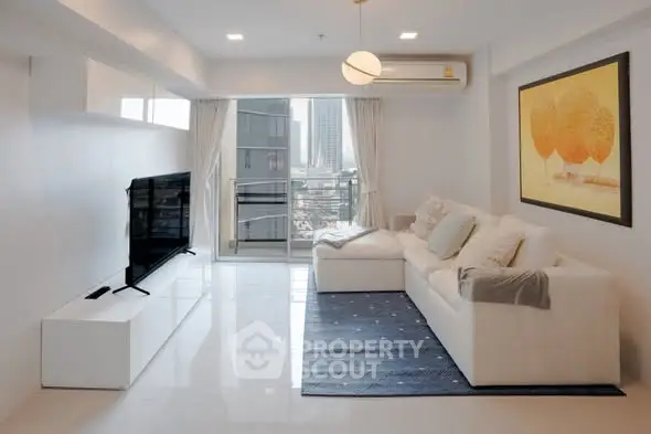 Modern living room with sleek white sofa, wall-mounted TV, and city view balcony.