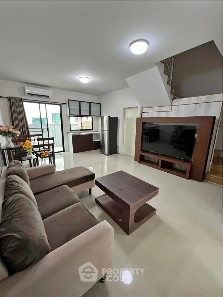 Spacious modern living room with sleek furniture and large TV, perfect for relaxation.