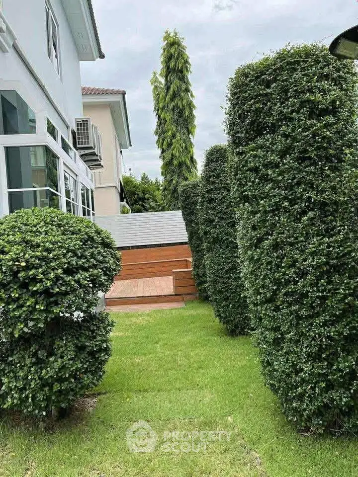 Charming garden pathway with lush greenery leading to a modern home entrance, perfect for nature lovers.