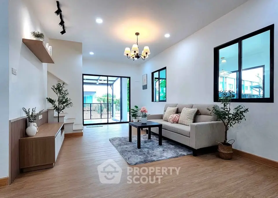 Modern living room with elegant decor and natural light, featuring a cozy sofa and stylish chandelier.