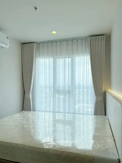 Bright bedroom with large window and city view, featuring elegant curtains and modern design.