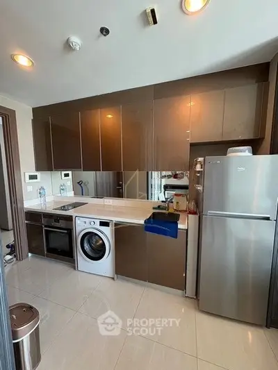 Modern kitchen with sleek cabinets, stainless steel appliances, and integrated washer-dryer.