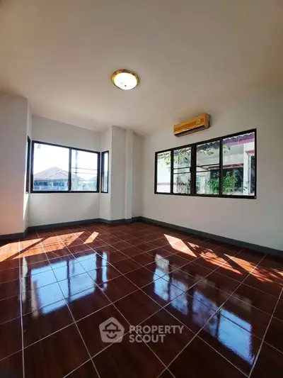 Spacious sunlit room with large windows and glossy tiled floor, perfect for a modern living space.