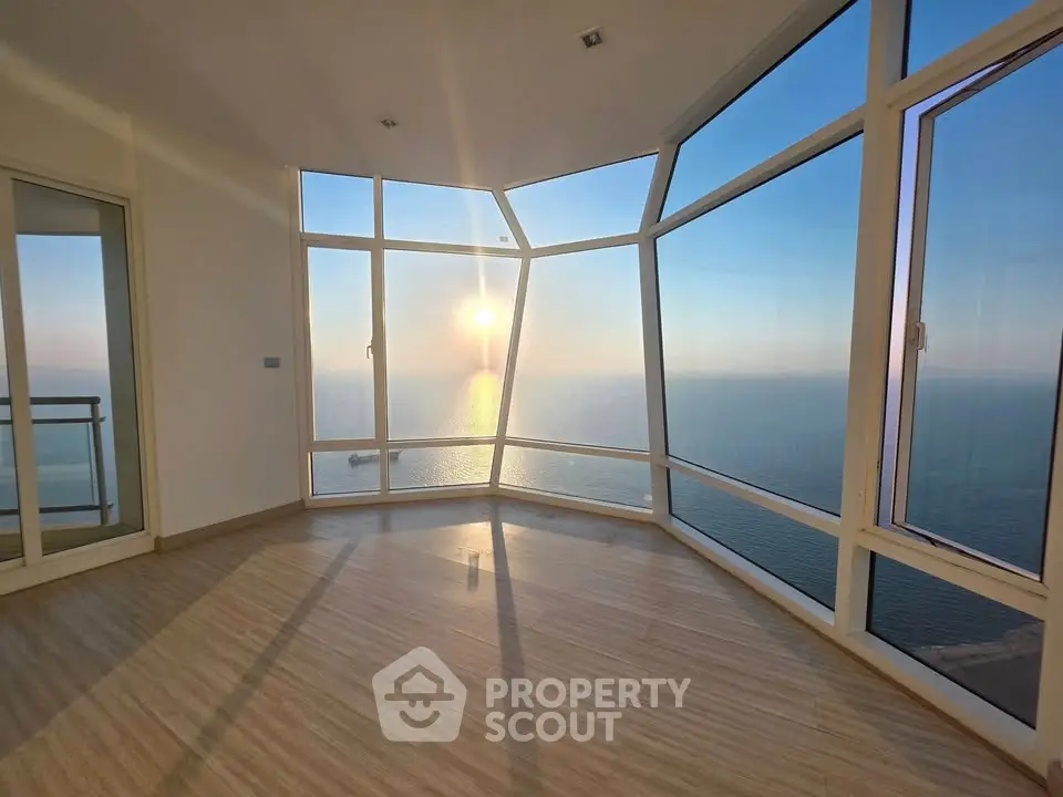 Stunning ocean view from modern high-rise apartment with floor-to-ceiling windows.