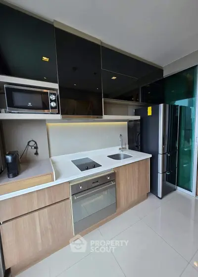 Modern kitchen with sleek appliances and open layout, featuring a built-in oven and glass-front cabinets.