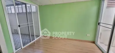 Spacious room with green walls and sliding glass doors leading to a balcony, perfect for natural light.