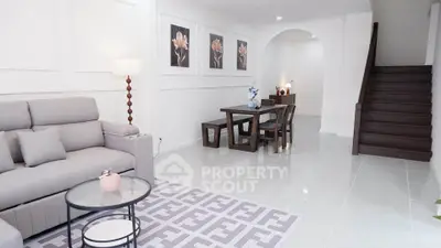 Elegant living room with modern decor and stylish dining area, featuring a cozy sofa and chic artwork.