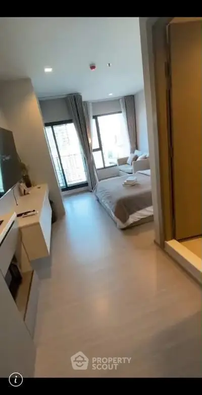 Modern bedroom with large windows and stylish decor in a contemporary apartment.