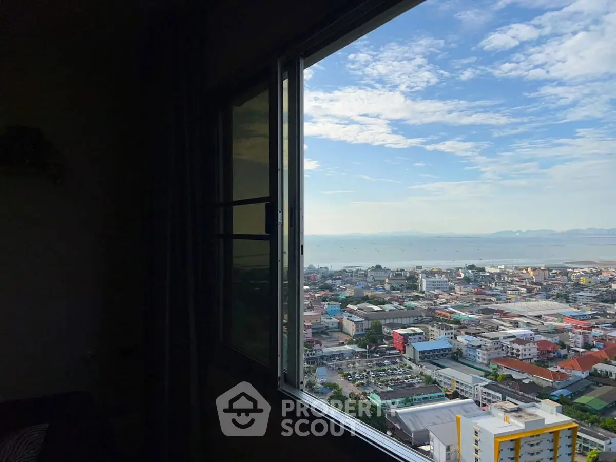 Stunning cityscape view from a high-rise apartment window overlooking the ocean.