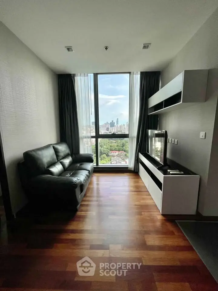 Modern living room with city view, sleek furniture, and wooden flooring.