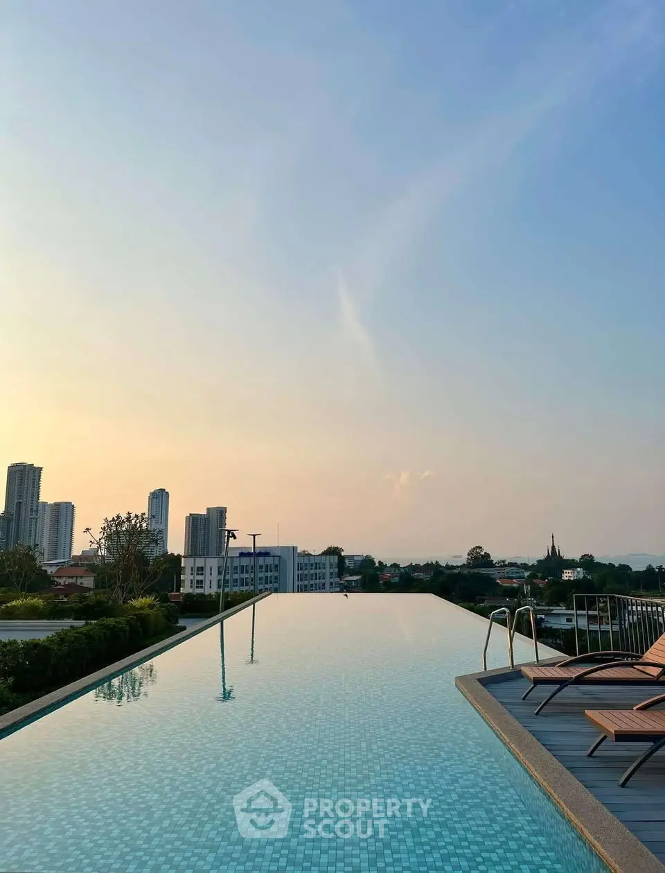 Stunning rooftop infinity pool with city skyline view at sunset, perfect for luxury living.