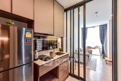Modern kitchen with sleek appliances and open layout leading to a cozy living room with natural light.