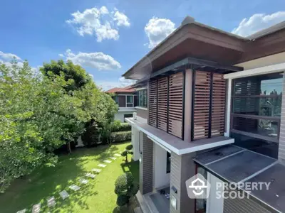 Modern two-story house with lush garden and clear blue sky