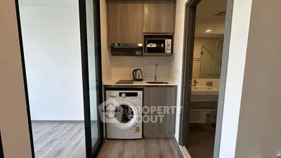 Compact kitchen with washing machine and modern appliances in stylish apartment.