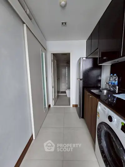 Modern kitchen with sleek appliances and washing machine in compact layout