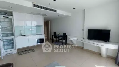 Modern open-plan living room with sleek kitchen and dining area, featuring minimalist design and natural light.