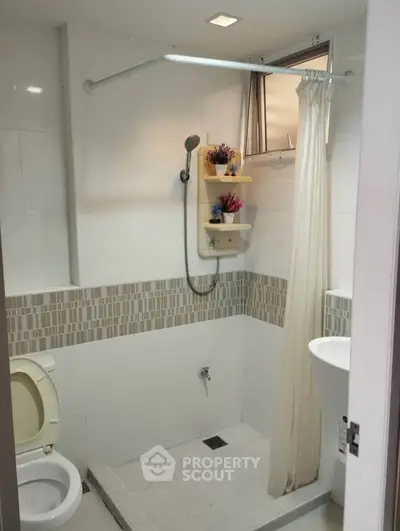 Modern bathroom with shower and white tiles, featuring a compact design and functional layout.
