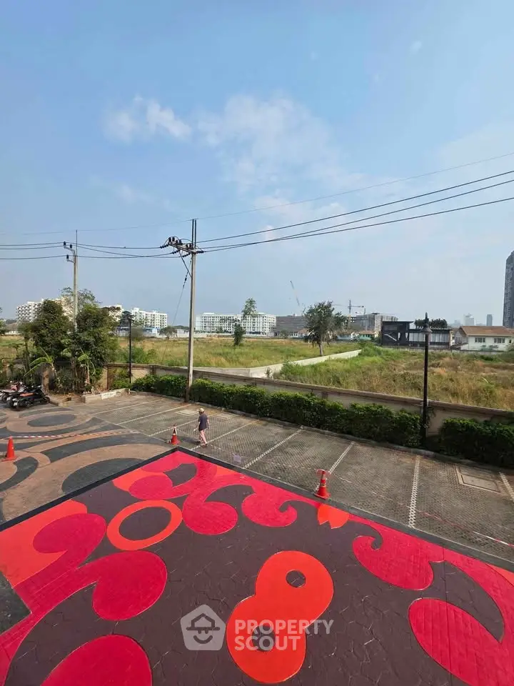 Spacious parking area with vibrant design and scenic view of nearby buildings and greenery.