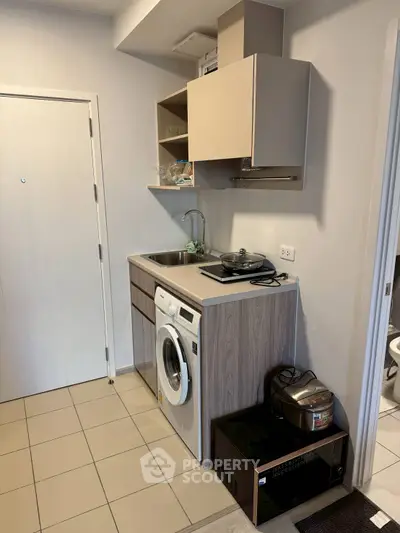 Compact kitchen with washing machine and modern appliances in cozy apartment