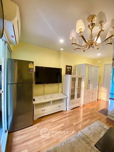 Charming living room with elegant chandelier and modern appliances in cozy apartment.