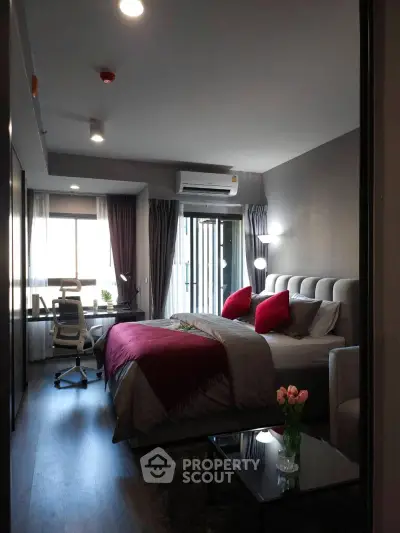 Modern bedroom with stylish decor and workspace, featuring a cozy bed and natural light.