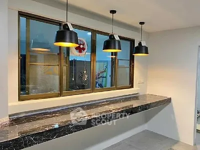 Modern kitchen with sleek marble countertop and stylish pendant lighting.