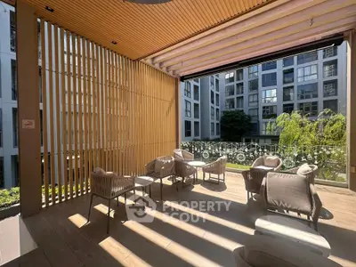 Modern outdoor seating area with stylish chairs and wooden slats, overlooking a contemporary apartment complex.