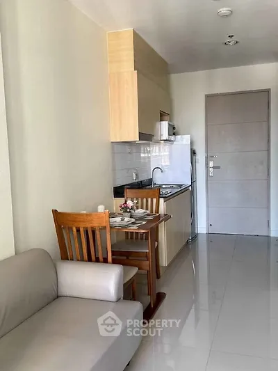 Modern compact kitchen with dining area in a cozy apartment, featuring sleek cabinetry and a comfortable sofa.